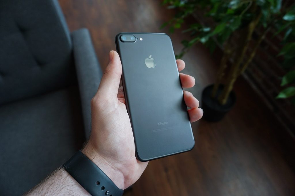 A hand holding a black smartphone indoors